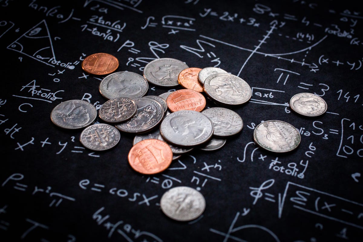 Monedas sobre una mesa marcada con fórmulas matemáticas