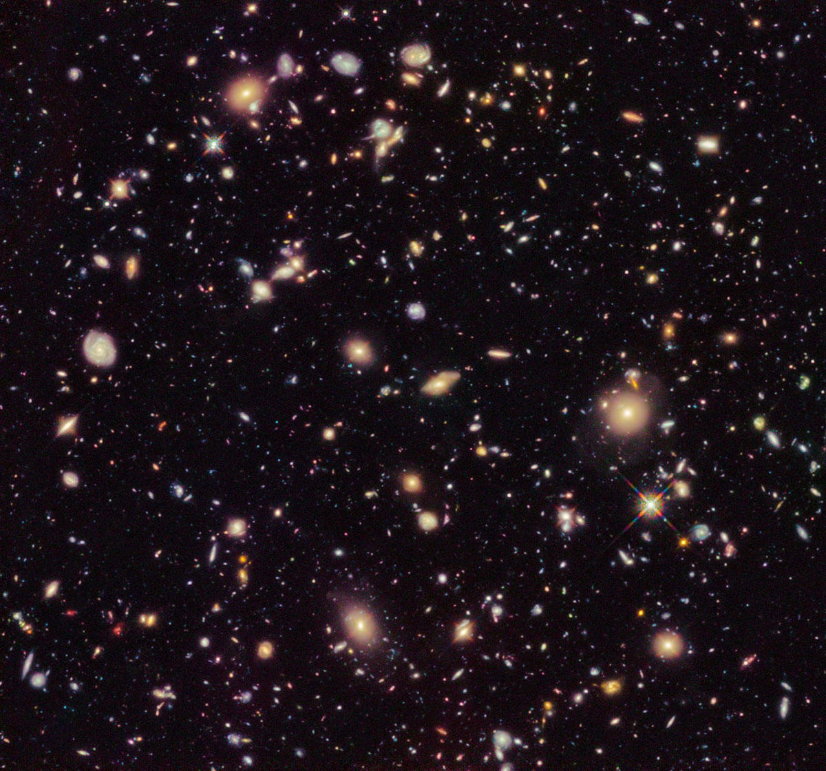 A spray of galaxies and stars looking small against the darkness of space.