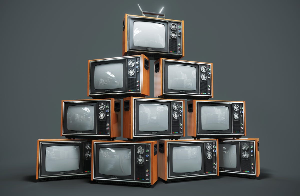 Pyramid of old tube style CRT TVs on flat gray background.