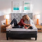 the Layla memory foam mattress in a bedroom with two people sitting on top of it.