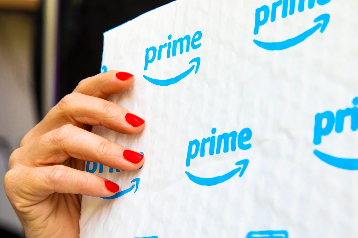 A hand with red fingernails holding an Amazon bubble mailer