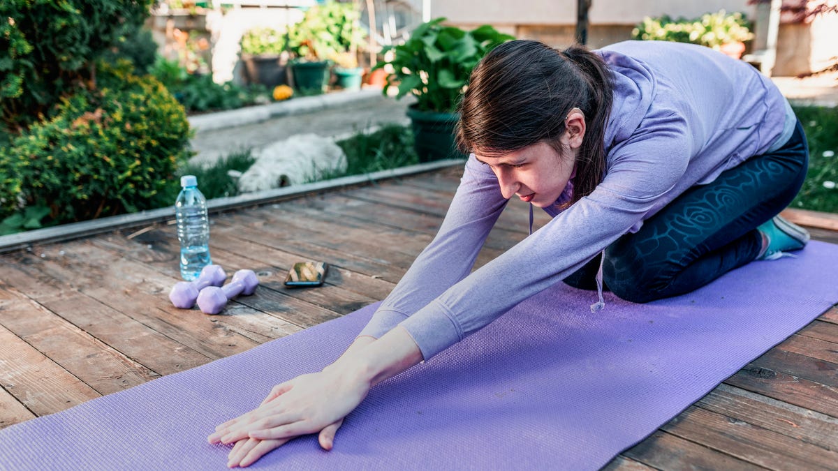 Woman wearing hearing aid stretching on yoga mat