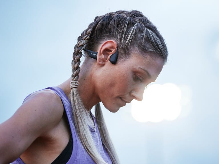 A woman using Shokz open-ear headphones during a workout
