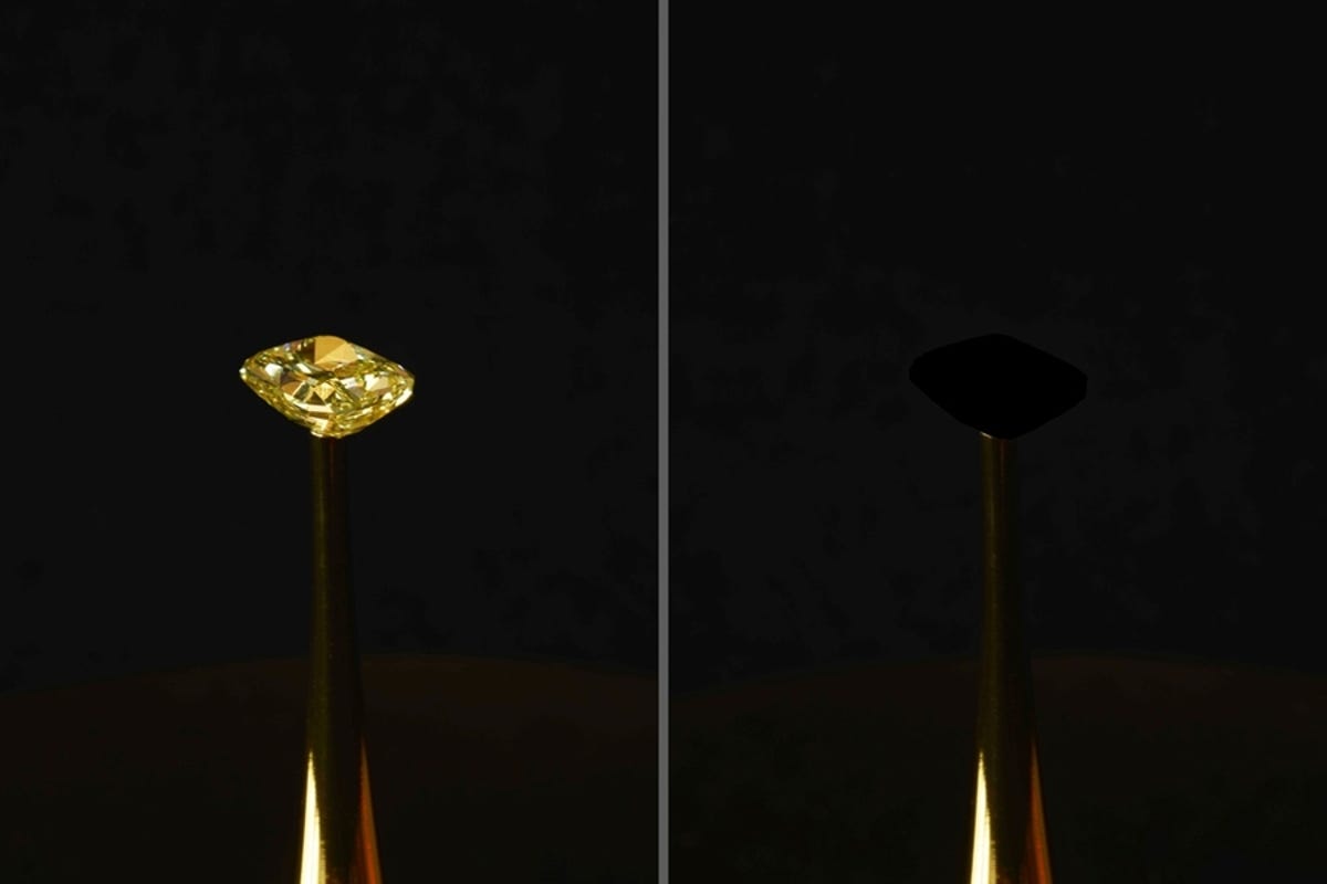 Two images are seen side-by-side. On the left, there's a yellow gem in front of a black background. On the right is the same setup, except the gem is covered in MIT's blackest black coating. It basically looks as though it disappeared.
