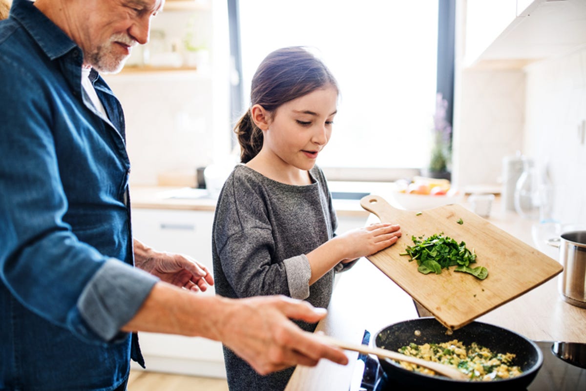 Grandfather and granddaughter prepare a healthy meal together.