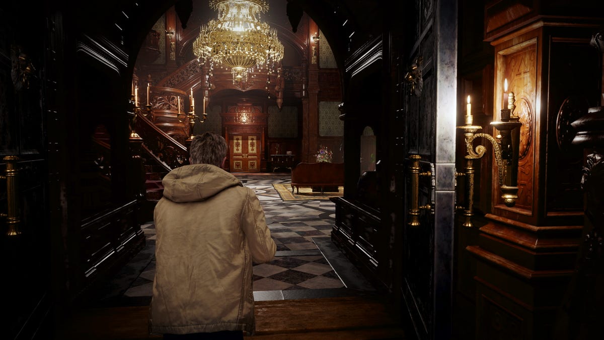 Ethan Winters, seen from behind, walks into Castle Dimitrescu's main hall in Resident Evil Village