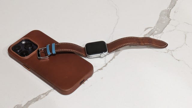 Leather watch strap on an apple watch laying on an iPhone 14
