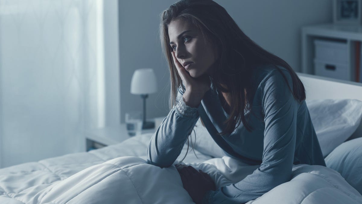Woman sitting awake in bed while unable to sleep