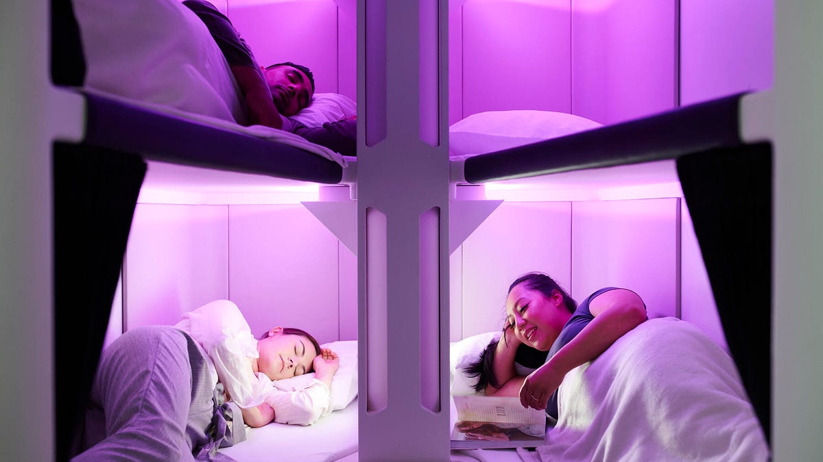 Four bunks on an airplane with people resting