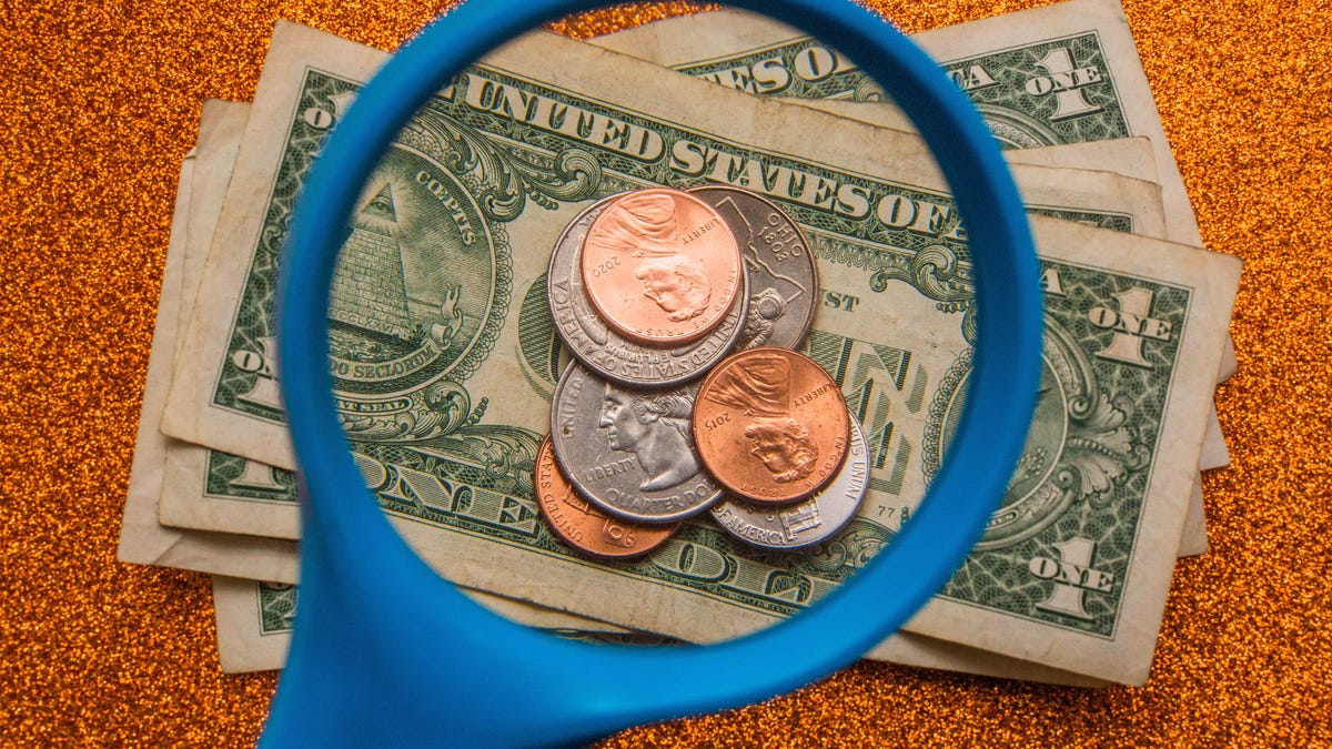 Viewing dollar bills and assorted coins through a magnifying glass