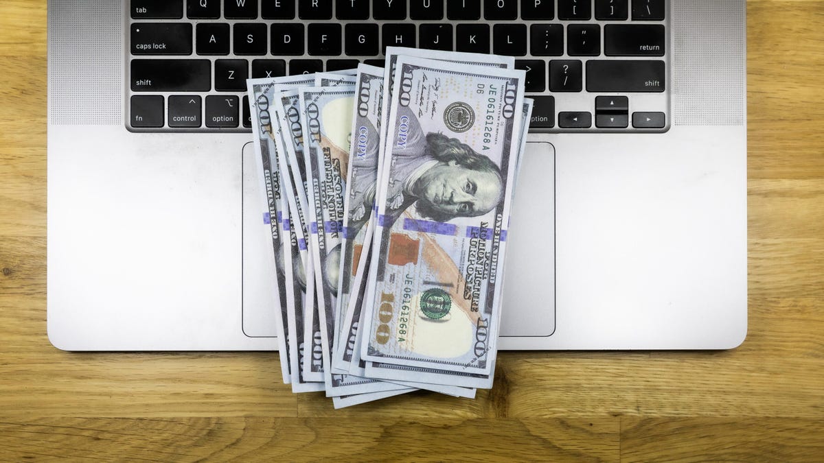 $100 bills lying on a laptop keyboard