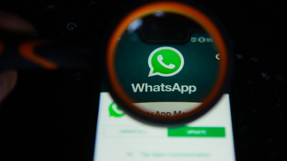 WhatsApp logo is seen trough a magnifying glass on an